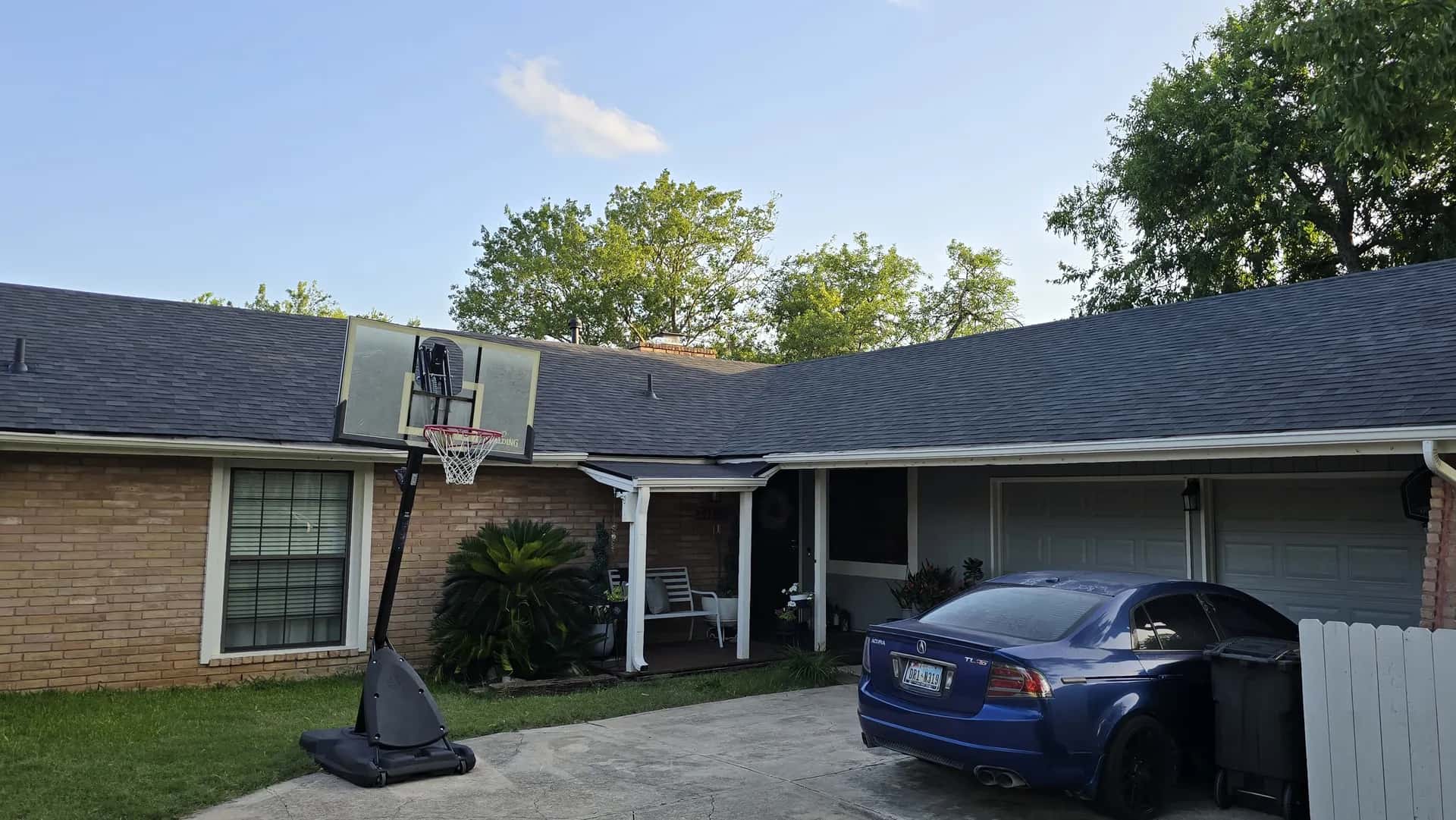 Single-story brick ranch home with a completed new dark gray architectural shingle roof, front view with driveway.