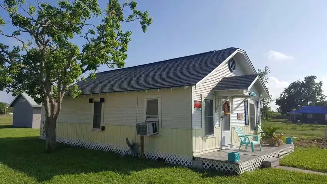 Small white cottage with a new gray architectural shingle roof and covered front porch.