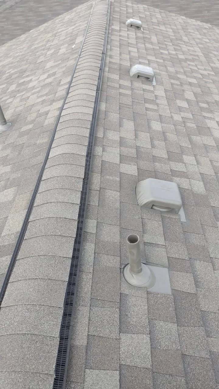 New light gray shingle roof with a ridge vent and pipe boot flashings
