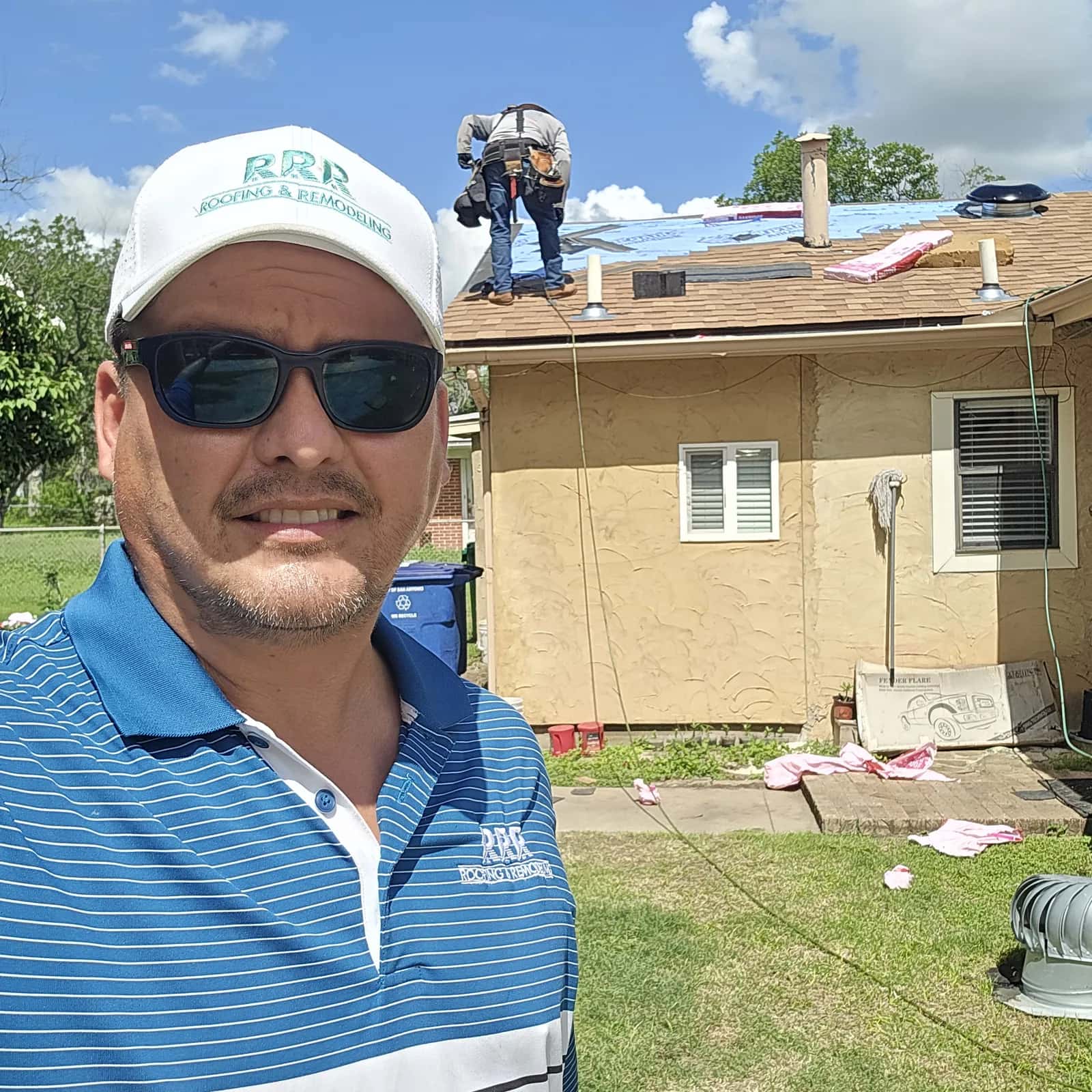 Texas-RRR owner Charlie Carreon in an RRR cap and polo shirt at a residential job site, crew working behind him